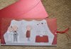 Esküvői meghívó - 210x105 mm - piros szalaggal jobbra kihúzható betétlappal -  a házasulandó pár leül az anyakönyvvezető elé - hozzáillő fényes bordó borítékkal